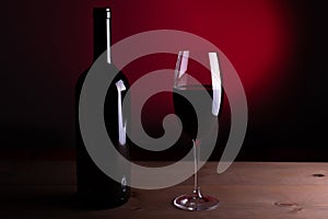 Black bottle of red wine and a glass. A bottle of wine stands on a table, a bottle on a gray background and a wooden table. Red