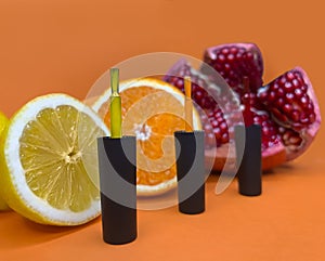 Black bottles of nail polish on a orange background with fruits