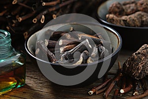 Bowl of Common comfrey or symphytum officinale roots. Bottle of infusion or tincture. Dried comfrey officinalis roots, Bistoret.