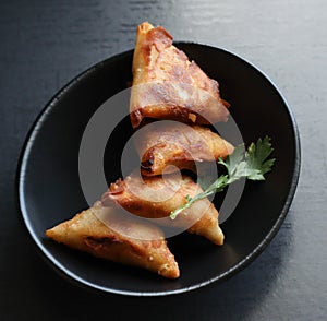 A black bowl of fried samosas