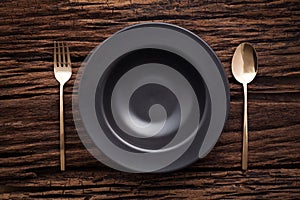 Black bowl plate fork spoon on wooden table background