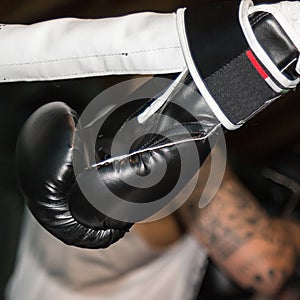 Black Boxing Glove Tied to Ring Ropes