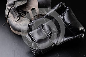 Black boxing gloves and old military boots. Training accessories