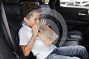 Black boy in car backseat breathing in paper bag