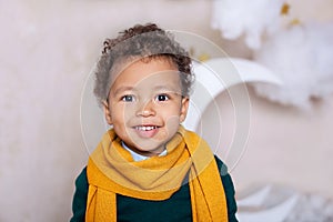 Black boy close up Portrait . Portrait of a cheerful smiling boy in a yellow scarf. The baby is smiling. Little African American.