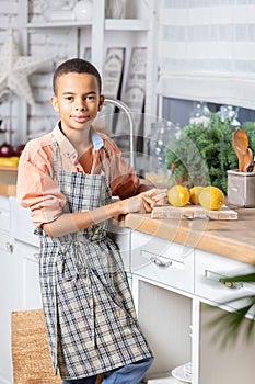 Black boy kid cooking fresh lemon on kitchen at home. African child preparing on table.