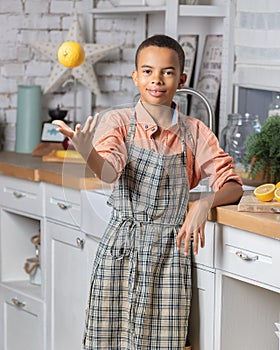 Black boy kid cooking fresh lemon on kitchen at home. African child preparing on table.