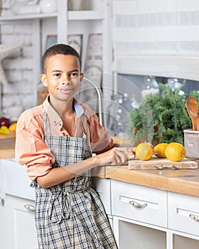 Black boy kid cooking fresh lemon on kitchen at home. African child preparing on table.