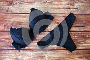 Black bras and panties on wooden background