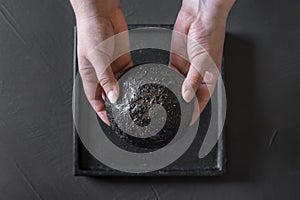 Black bread bun held in hands. Strange food