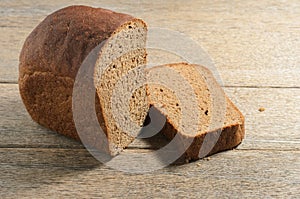 Black bread made of rye flour against the background of old village ash planks.