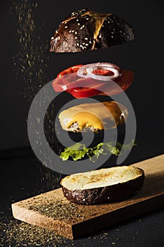 Burger with cheese onion black bread  salad tomato photo