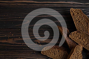 Black bread.  A sliced â€‹â€‹dark baguette lies on a wooden background from dark brown boards.