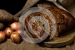 Black bread and vegetables on a black background. Borodino bread. Homemade baking