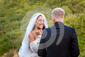 Black bride talking on the phone and looking happily at her white husband