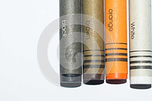 Black, brown, orange and white crayons with a color names written on a crayon