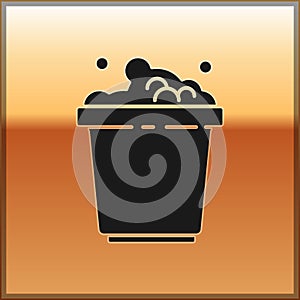 Black Bucket with soap suds icon isolated on gold background. Bowl with water. Washing clothes, cleaning equipment. Vector