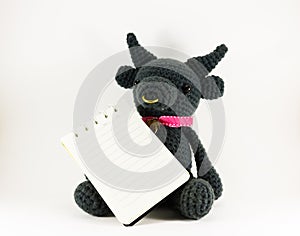 Black buffalo doll and notebook on white background isolated.