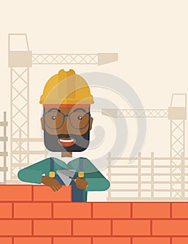 Black builder man is building a brick wall photo