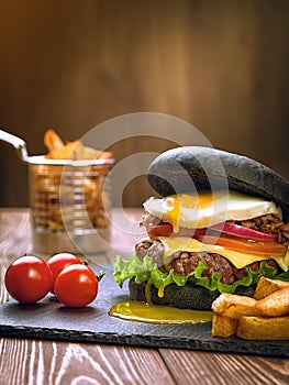 Black burger with an egg on a stone plate.