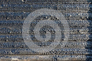 Black burnt wall of a rustic log house on a bright summer sunny day. Coals