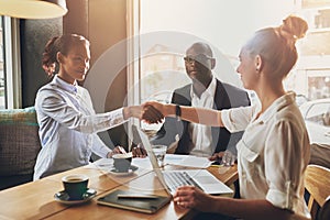 Black business woman and white business woman shaking hands