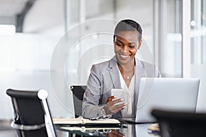 Black business woman working on laptop and using mobile phone