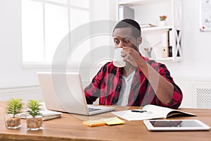 Black businessman in casual office, work with laptop and drinking coffee