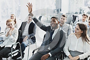 Black businessman having question at company seminar