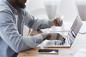 Black businessman paying his bills online with laptop and credit card