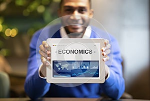 Black Businessman Showing Digital Tablet With Economics Graphs Sitting Indoors