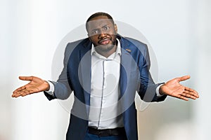 Black businessman shrugging shoulders.