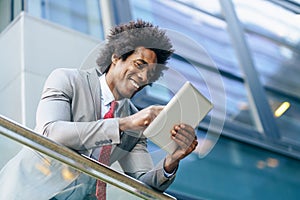 Black Businessman using a digital tablet sitting near an office building. photo