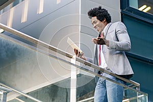 Black Businessman using a digital tablet sitting near an office building. photo