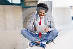 Black Businessman using a digital tablet sitting near an office building. photo