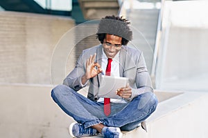 Black Businessman using a digital tablet sitting near an office building. photo