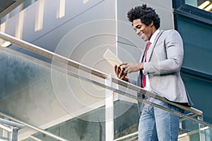 Black Businessman using a digital tablet sitting near an office building. photo