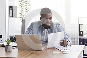 Black businessman working with documents in office, checking financial reports