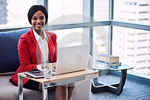 Black businesswoman smiling at the camera while seated on sofa