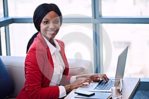 Black businesswoman smiling at the camera while seated on sofa