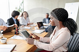 Black Businesswoman Using Digital Tablet Sitting During Corporate Meeting Indoor