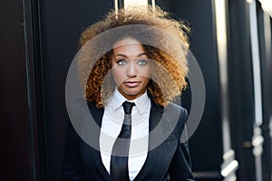 Black businesswoman wearing suit and tie in urban background