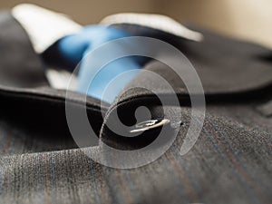 Black buttons on a man`s suit background with blue tie, close up