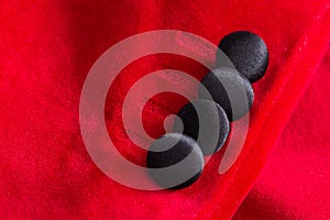 Black buttons on the red sleeve of the showman`s jacket, macro. Material