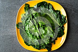 Black Cabbage Leaves / Organic Green Lacinato Kale on Yellow Plate with Grey Granit Surface