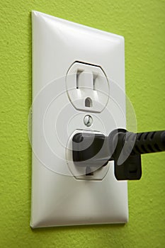 Black cable plugged in a white electric outlet photo