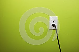 Black cable plugged in a white electric outlet