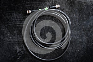 Black cable for transferring sdi signal through bnc connector on a dark background