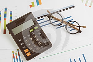 Black calculator, eyeglasses on monthly graph and chart on office table using as company profit and loss, financial and accounting