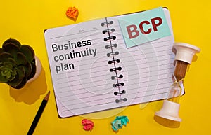 a black calculator, a pen, and a notebook with the text BCP Business Continuity Plan